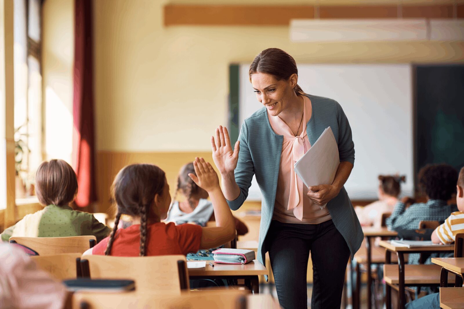 A teacher high-fives a student, demonstrating quality education and training delivery.