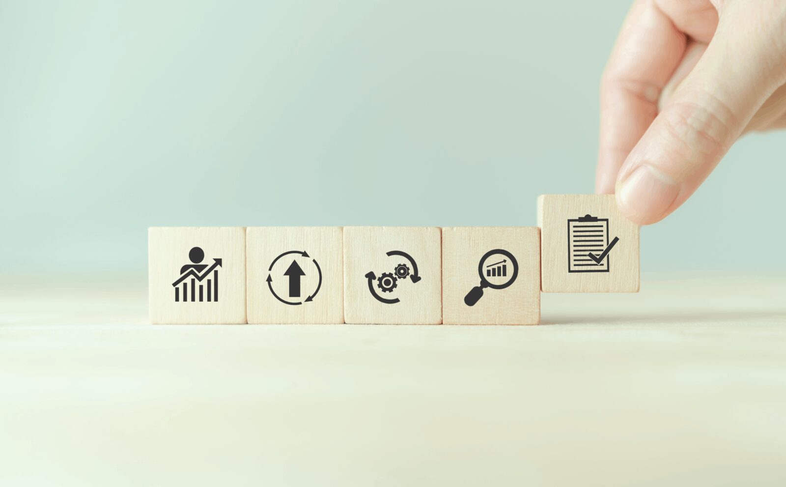 Wooden blocks with icons illustrate the quality assurance process for vocational education training resources.