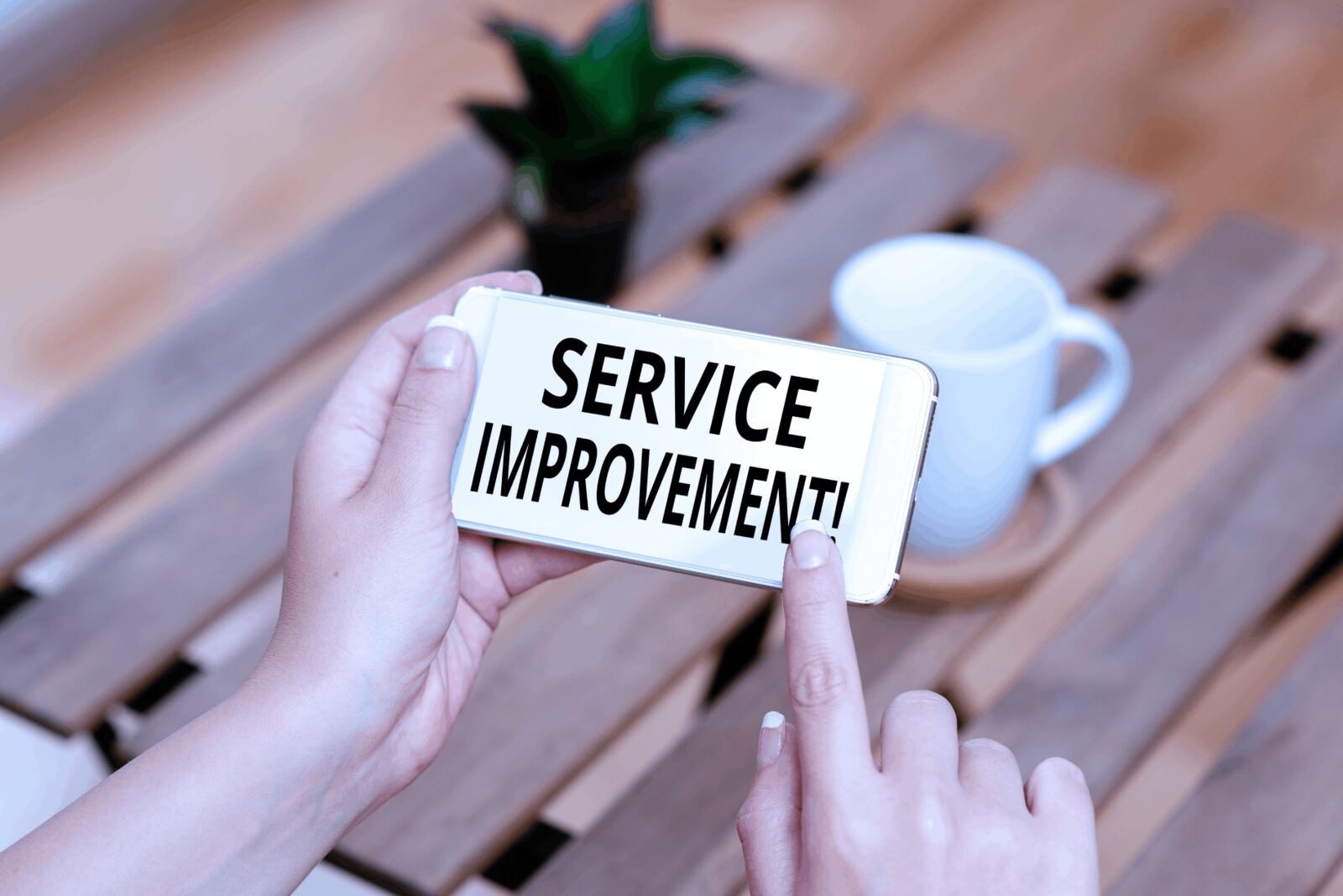 A hand holds a card reading 'Service Improvement!' next to a notebook and coffee, demonstrating our commitment to vet.