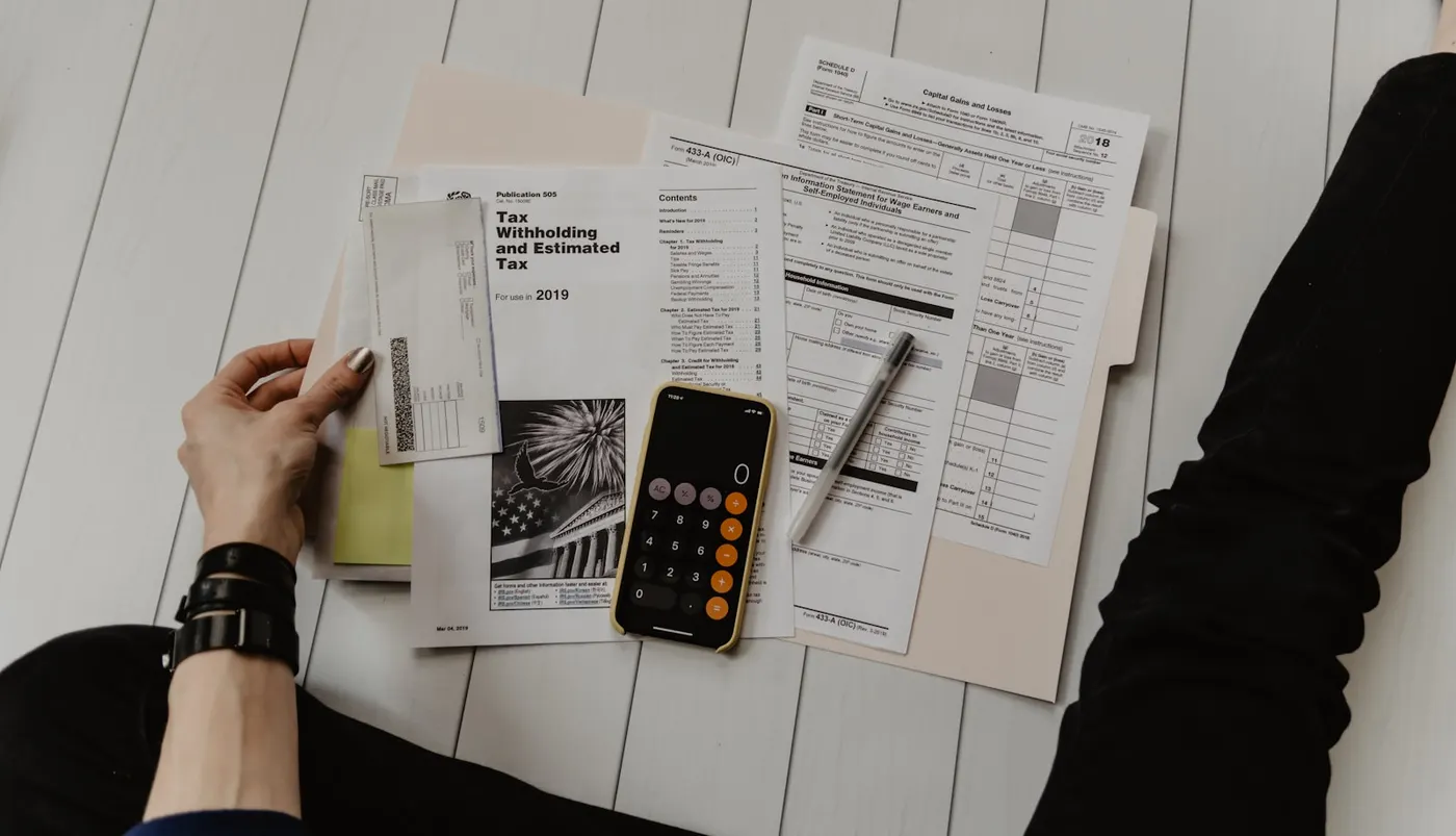 A person prepares taxes with forms, a calculator, and pen demonstrating RPL assessment skills for vocational education.
