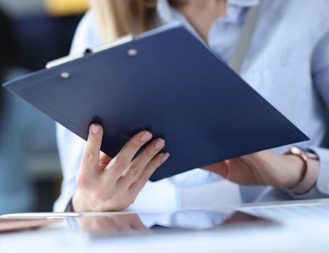 Assessor | Career Calling International A businesswoman reviews assessment documents on a clipboard, supporting vet compliance.