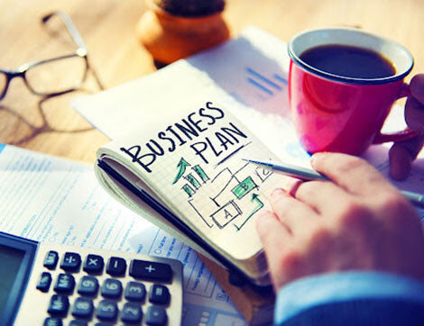 A person works on a business plan with financial documents and coffee, supporting vet compliance.