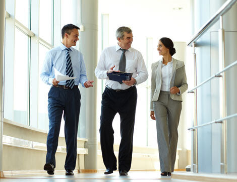Three business professionals walk and converse in a modern office building, demonstrating Career Calling International's.