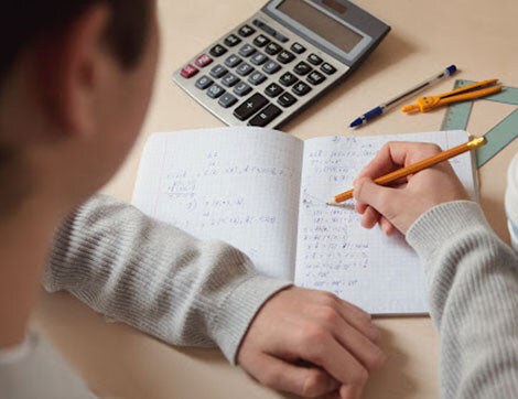 Student Studying | Career Calling International A person studies with a calculator, notebook and writing utensils on a desk for vet compliance.