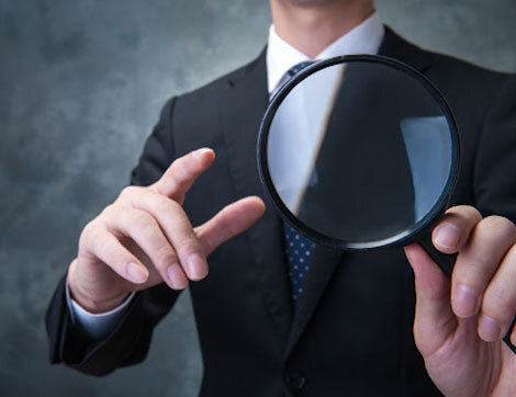 An auditor examining a document with a magnifying glass