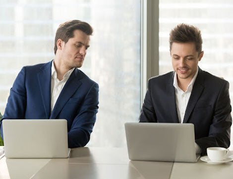 Two colleagues reviewing learning materials on laptops