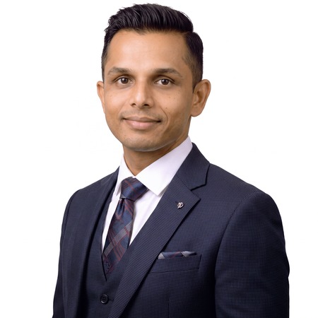 A man in a suit and tie poses for a professional headshot of Vijay Patel.